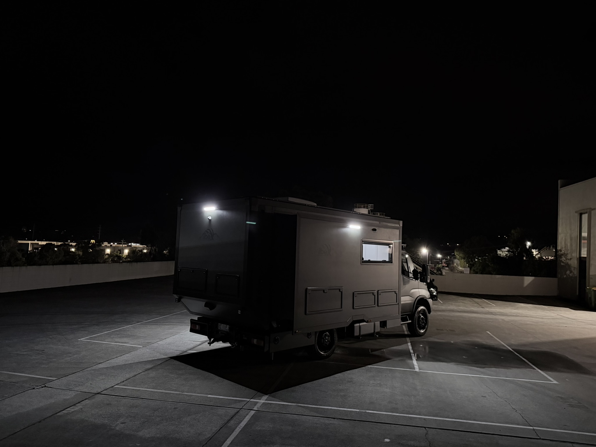 ibeX rear three-quarter view at night with city lights in background